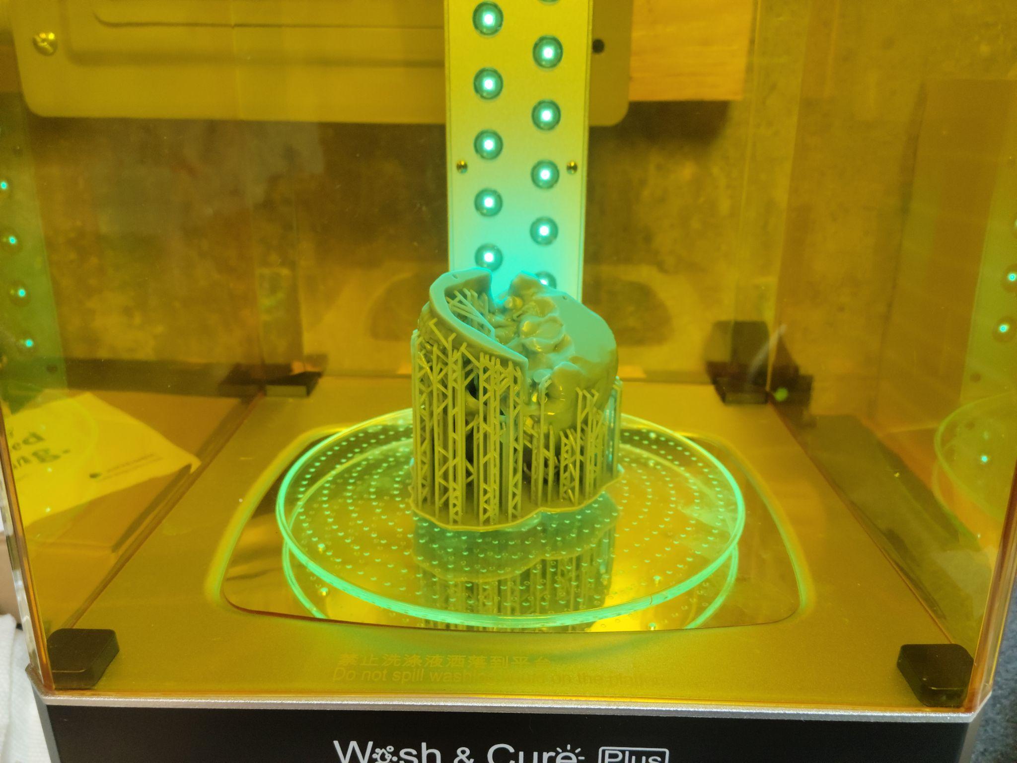Resin part under UV post-cure lamp — a required step after printing